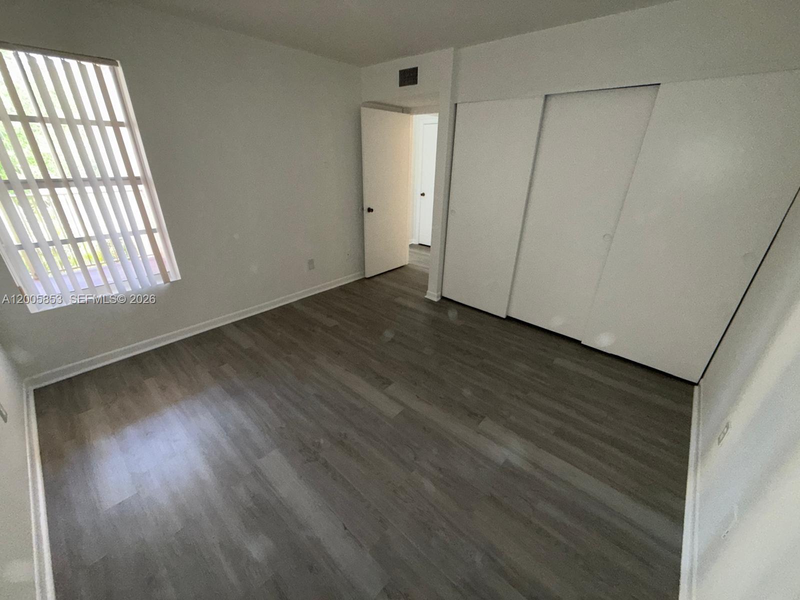15285 Southwest 107th Lane, Unit 214 Miami, FL 33196 - Photo 9 of 16 an empty room with wooden floor and windows