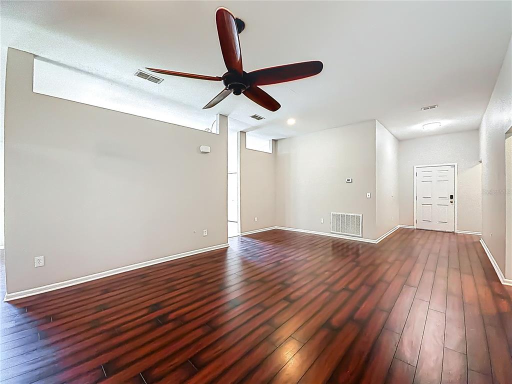 6358 Southwest 155th Place Ocala, FL 34473 - Photo 11 of 55 a view of an empty room with wooden floor and a ceiling fan