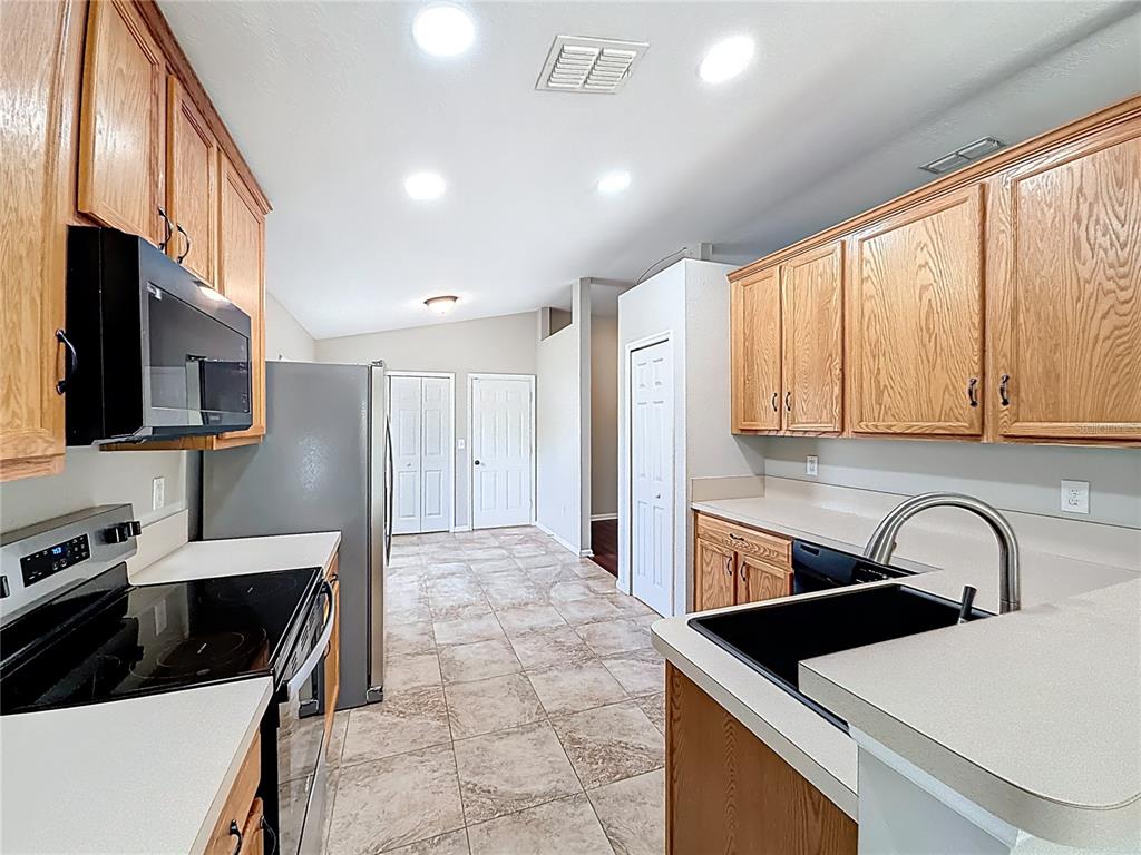 6358 Southwest 155th Place Ocala, FL 34473 - Photo 23 of 55 a kitchen with stainless steel appliances a sink a stove a microwave a sink a refrigerator and cabinets