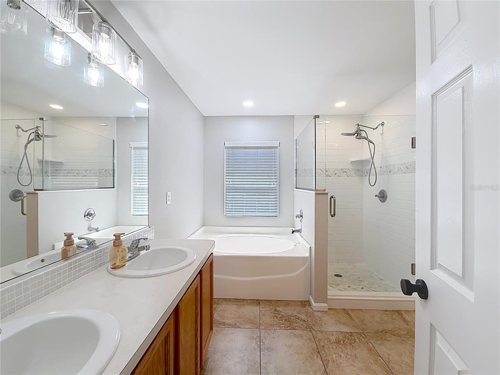 6358 Southwest 155th Place Ocala, FL 34473 - Photo 39 of 55 a bathroom with a granite countertop sink a mirror and a bathtub