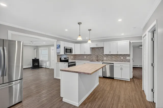 a kitchen with a center island wooden floor and stainless steel appliances