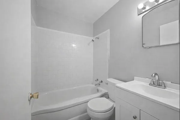 a bathroom with a bathtub shower sink vanity mirror and toilet