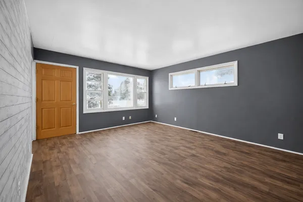 an empty room with wooden floor and windows