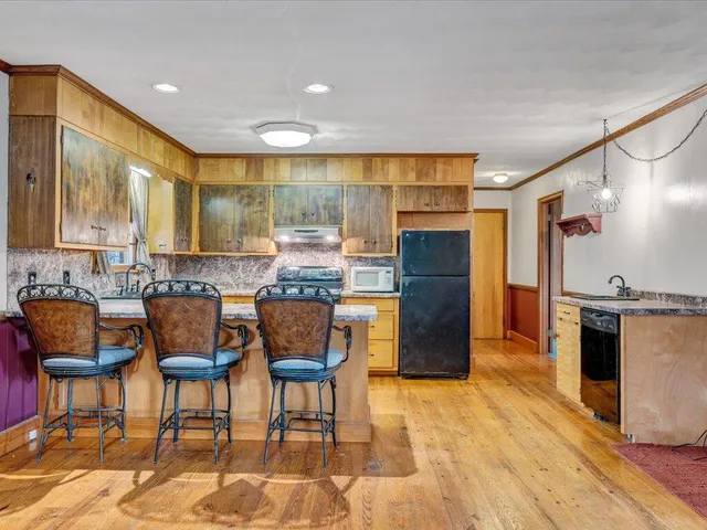 a kitchen with stainless steel appliances kitchen island granite countertop a refrigerator and cabinets