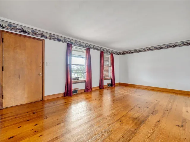a view of an empty room with window and wooden floor
