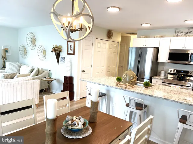 a kitchen with stainless steel appliances kitchen island granite countertop a dining table and chairs with wooden floor