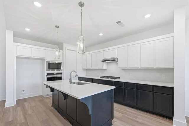 a kitchen with kitchen island a sink stainless steel appliances and cabinets
