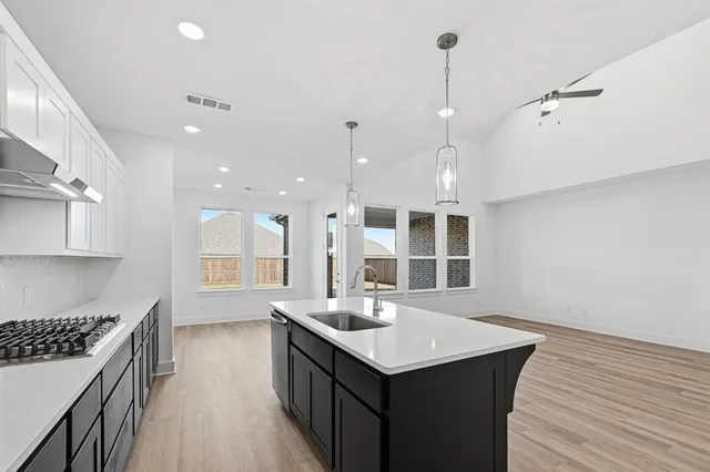 a kitchen with granite countertop a sink cabinets and wooden floor