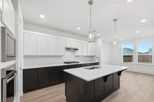 a kitchen with a sink a counter space appliances and cabinets