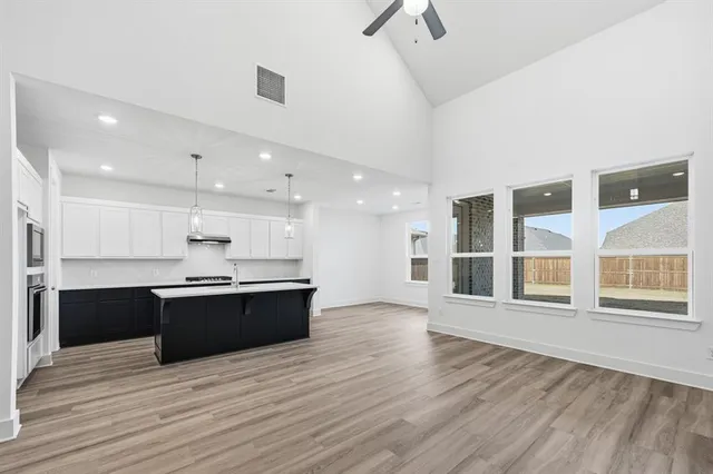 a large kitchen with stainless steel appliances kitchen island a large counter top and a wooden floors