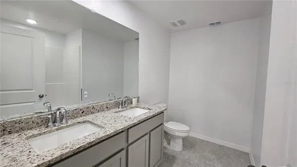 a bathroom with a granite countertop sink a toilet and a mirror