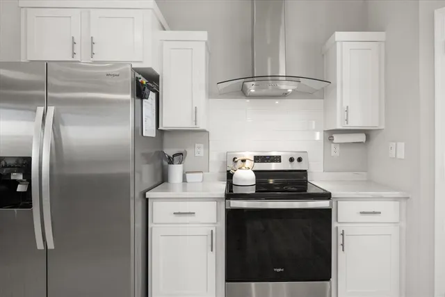 a kitchen with stainless steel appliances granite countertop a refrigerator a stove and white cabinets
