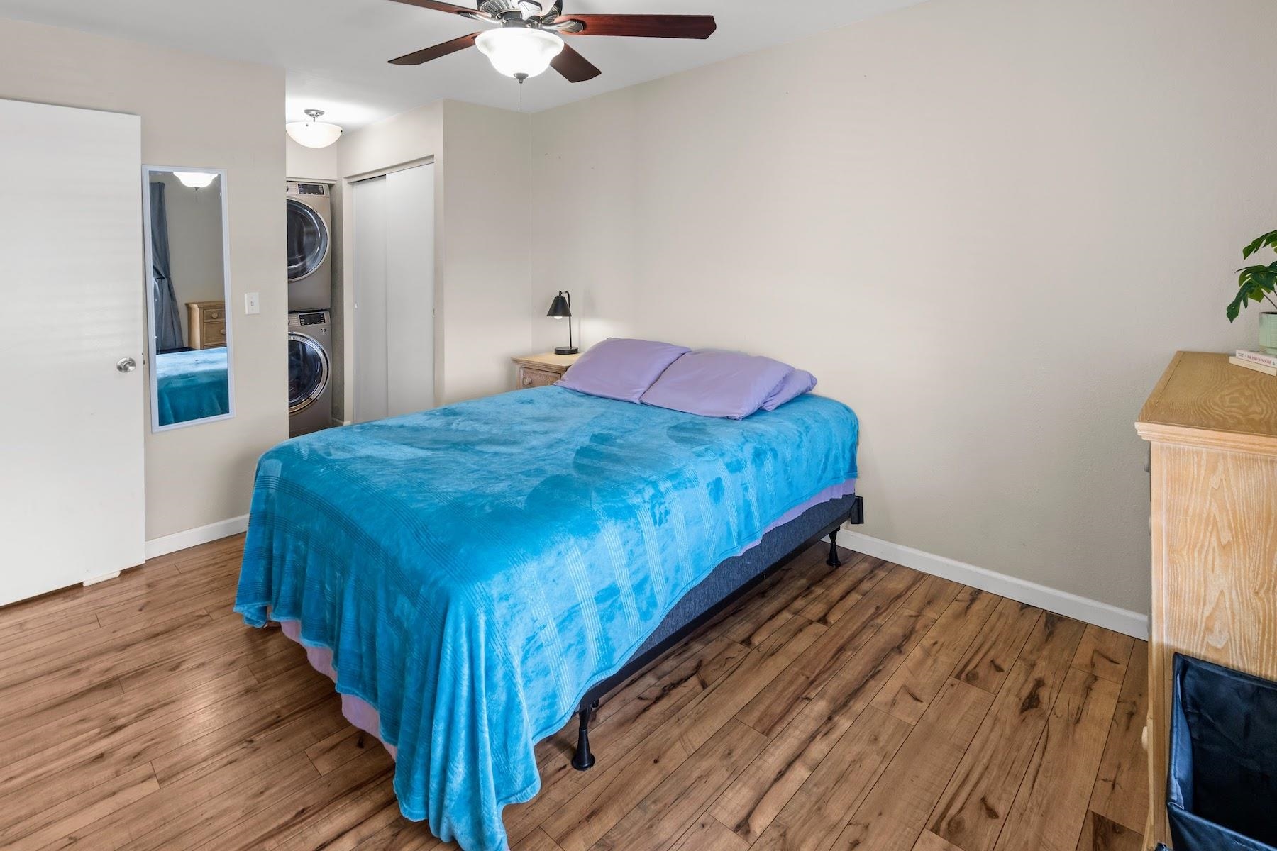 480 Kenolio Road, Unit 12201 Kihei, HI 96753 - Photo 13 of 25 a bed sitting in a spacious bedroom next to a bathroom with a sink and a mirror