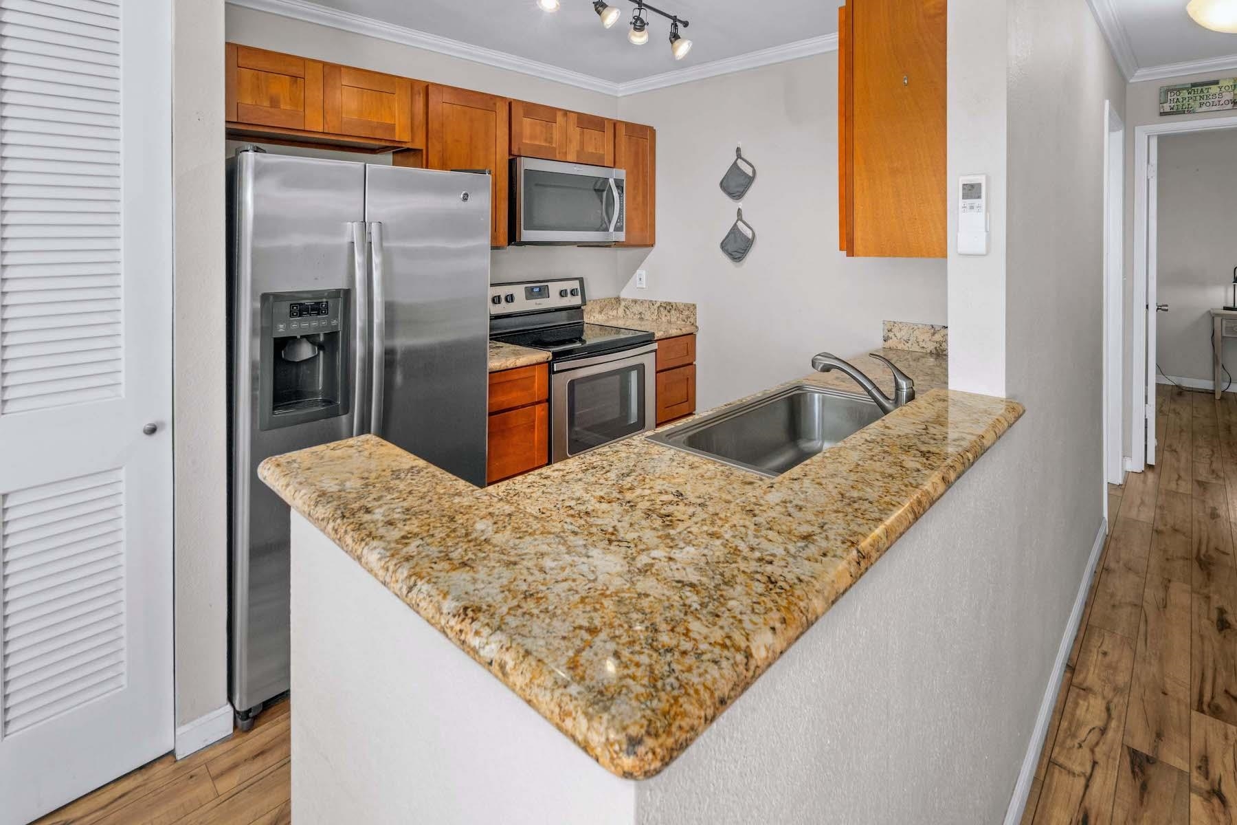 480 Kenolio Road, Unit 12201 Kihei, HI 96753 - Photo 3 of 25 a kitchen with stainless steel appliances granite countertop a sink refrigerator and microwave