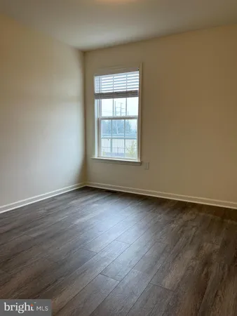 an empty room with wooden floor and window