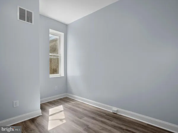 a view of an empty room with closet and wooden floor