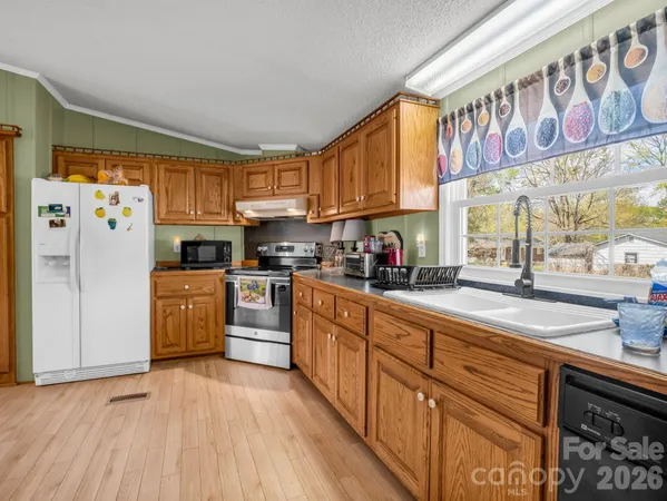 a kitchen with stainless steel appliances granite countertop a refrigerator a sink dishwasher a stove with wooden cabinets and floor