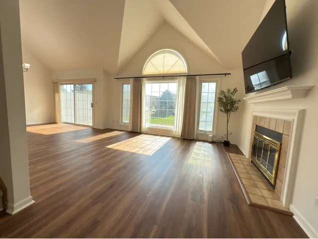 an empty room with wooden floor fireplace and windows