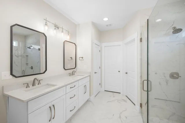 a bathroom with a double vanity sink a mirror and a shower