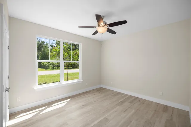 an empty room with wooden floor and ceiling fan