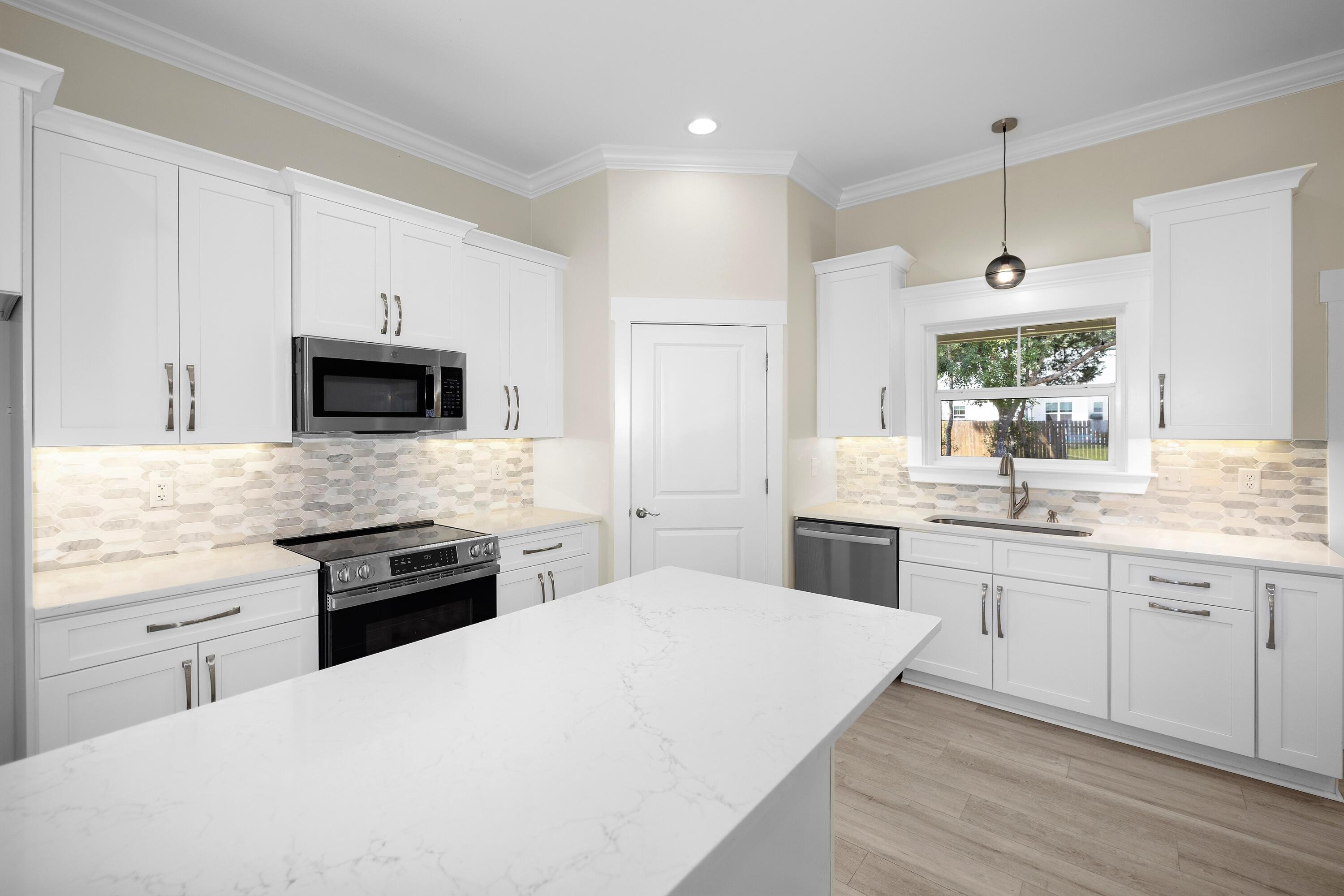 61 Spruce Street Freeport, FL 32439 - Photo 6 of 35 a large kitchen with a stove top oven a sink a microwave and wooden floor