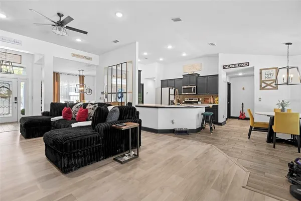 a dining room with stainless steel appliances kitchen island granite countertop a table chairs and a refrigerator