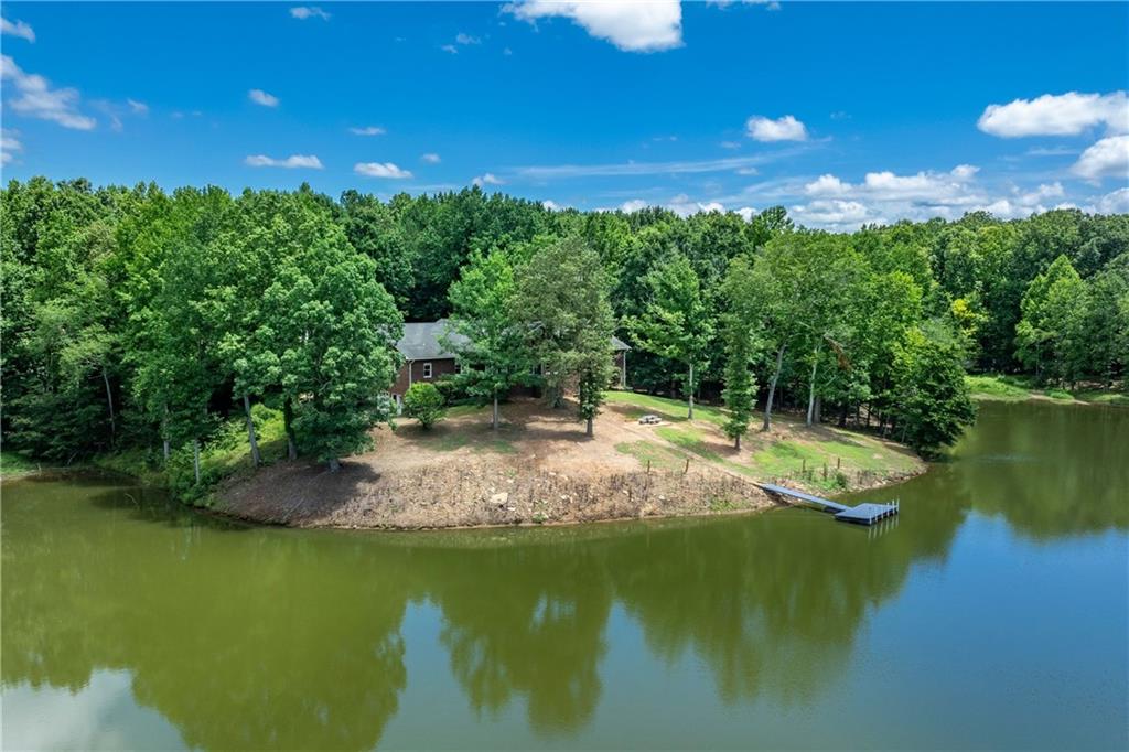 a view of a lake with lawn chairs and large trees