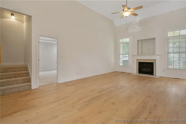 an empty room with wooden floor fireplace and windows