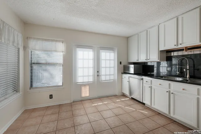 a kitchen with white cabinets a sink a window and a counter top space