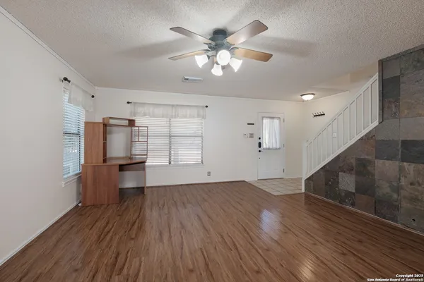 a view of empty room with wooden floor and ceiling fan