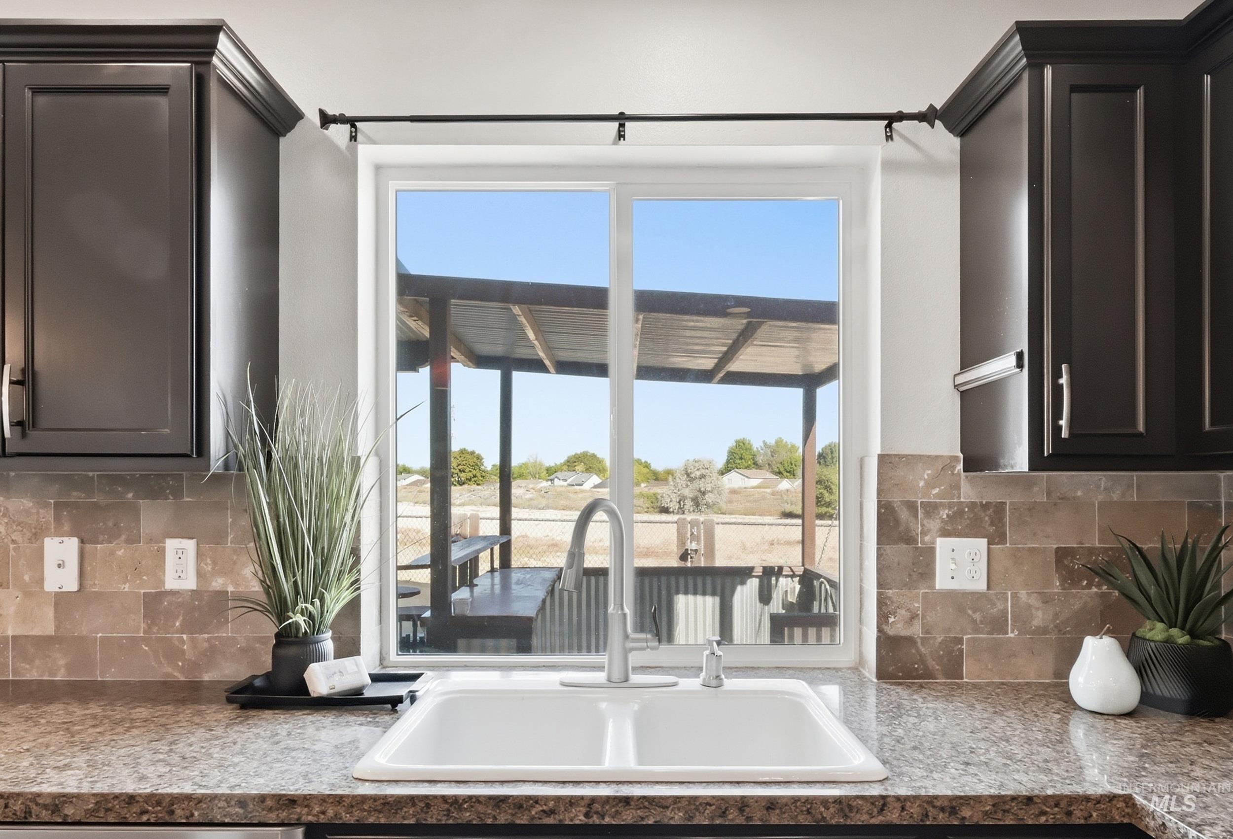 4855 South Chex Way Boise, ID 83709 - Photo 15 of 47 Kitchen sink with an integrated faucet, surrounded by granite-finish countertops and a tiled backsplash