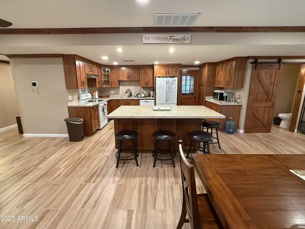 a dining hall with stainless steel appliances a dining table chairs and a wooden floor