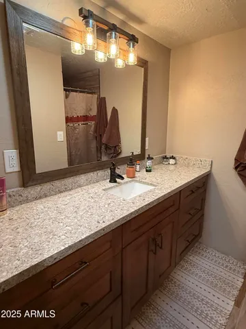 a bathroom with a granite countertop sink and a mirror