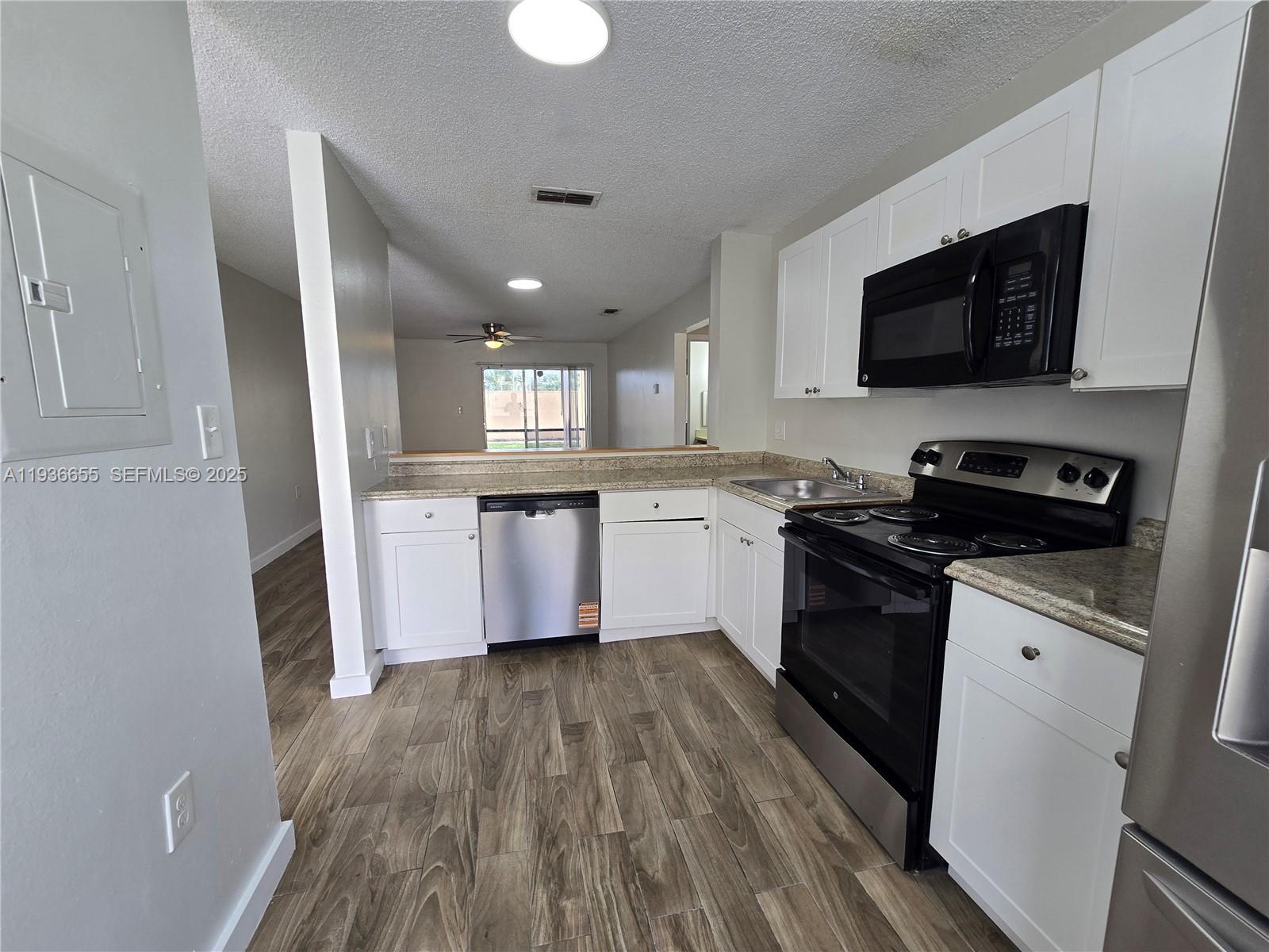 2153 Southwest 80th Terrace, Unit 2153 Miramar, FL 33025 - Photo 4 of 15 a kitchen with stainless steel appliances granite countertop a stove top oven a sink dishwasher and a microwave with wooden floor