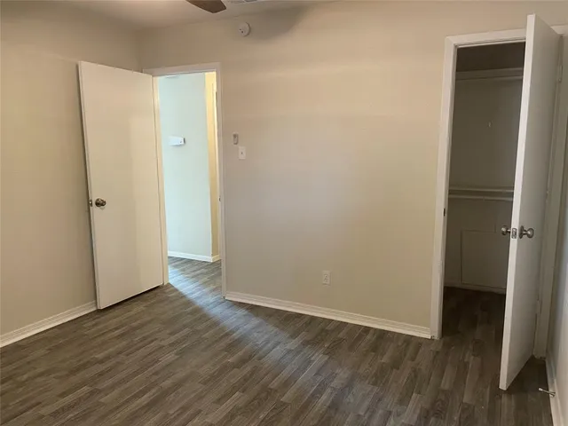 a view of an empty room with wooden floor and closet