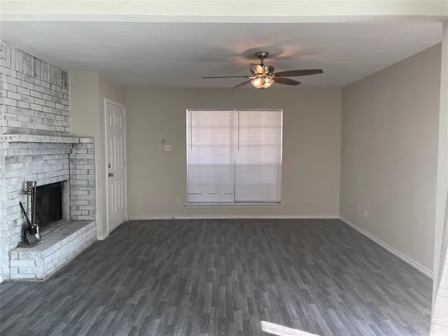 a view of an empty room with wooden floor fireplace and a window
