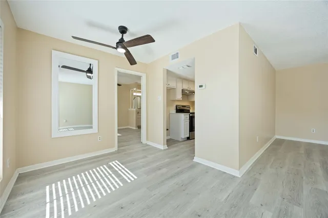 a view of empty room with wooden floor and ceiling fan