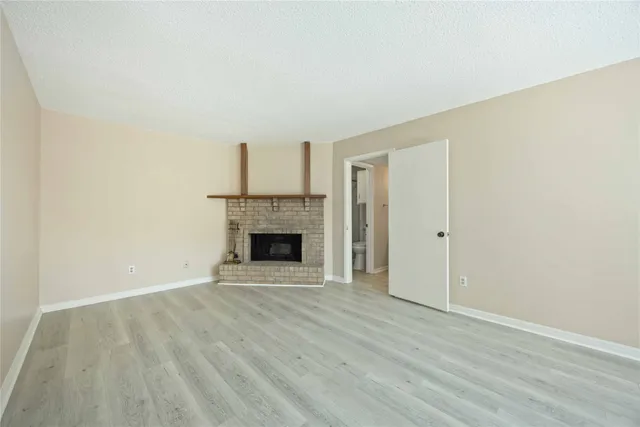 a view of empty room with wooden floor and fireplace