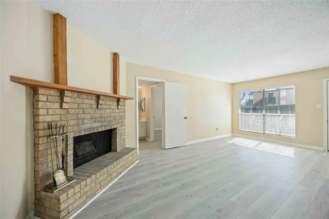 a view of empty room with wooden floor and fireplace