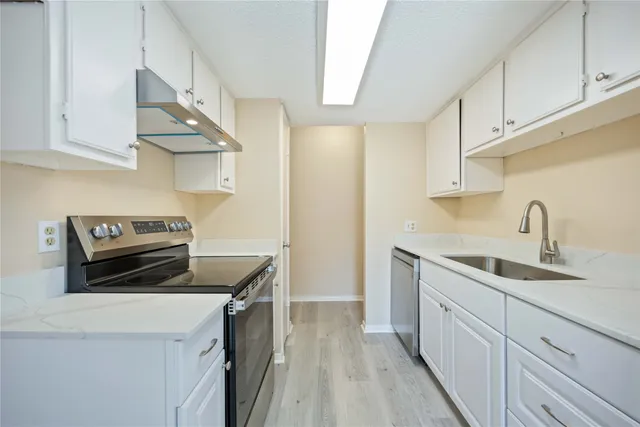 a kitchen with white cabinets sink and stove