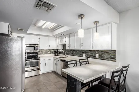 a kitchen with a stove a sink and chairs