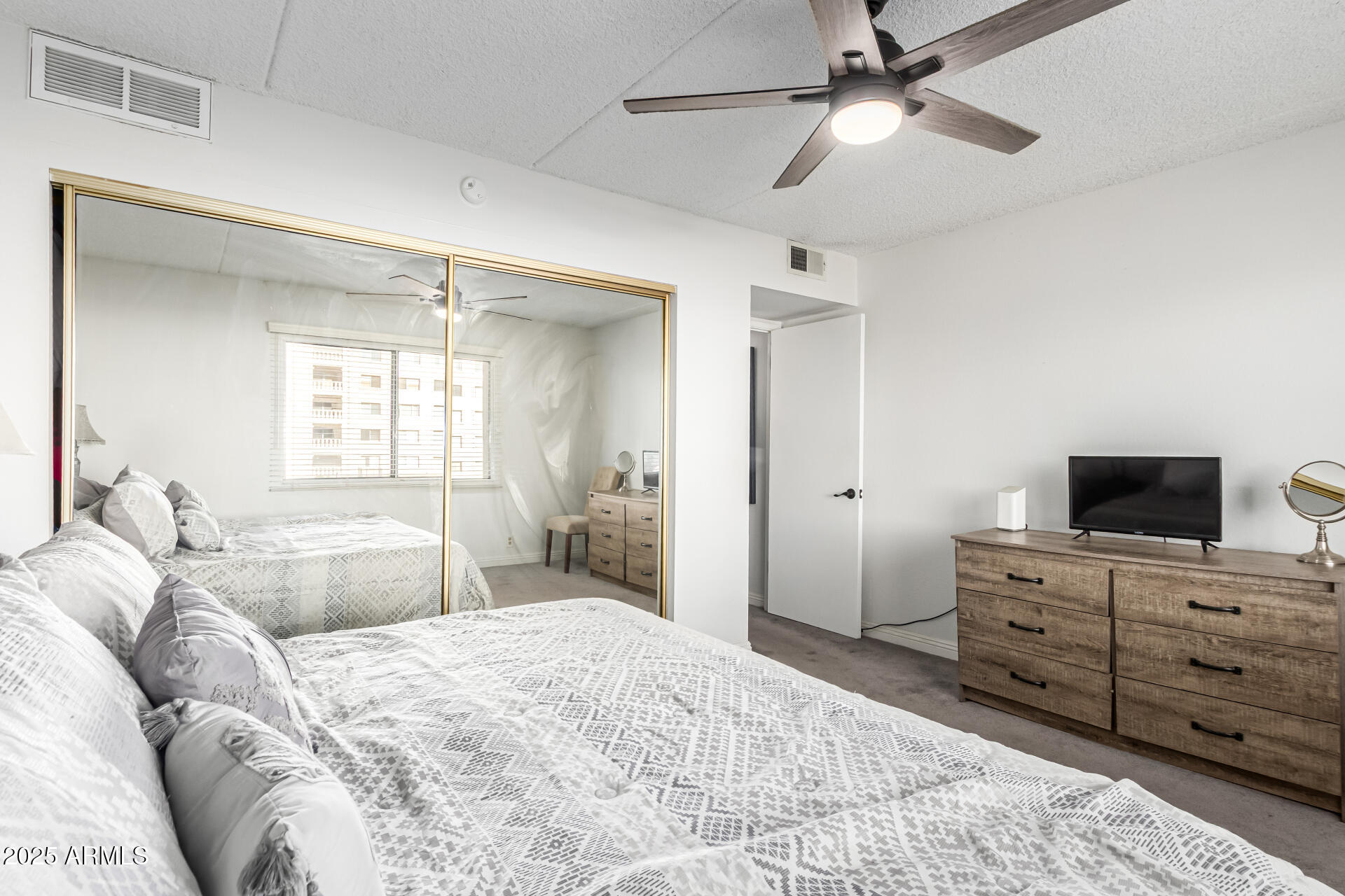 7910 East Camelback Road, Unit 203 Scottsdale, AZ 85251 - Photo 5 of 12 a bedroom with a large bed and a flat tv screen on dresser