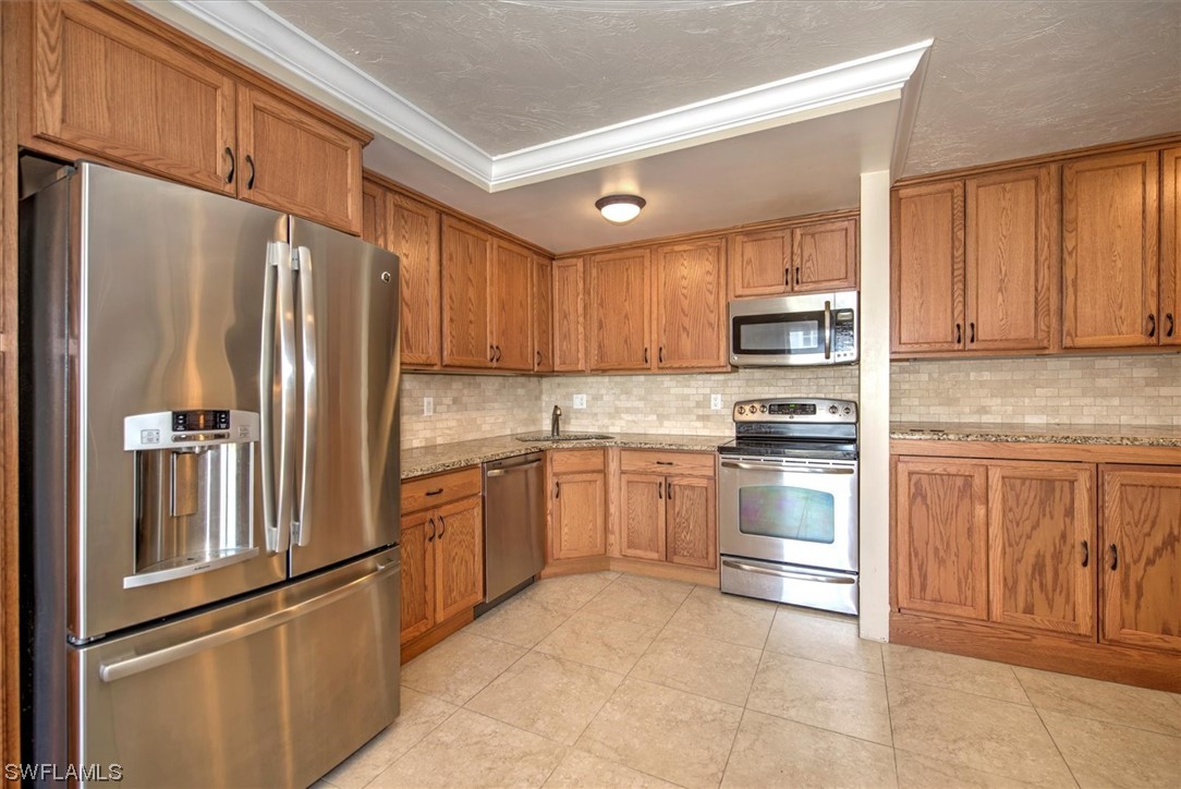 828 Wiggins Pass Road, Unit 10 Naples, FL 34110 - Photo 7 of 17 a kitchen with granite countertop stainless steel appliances and refrigerator