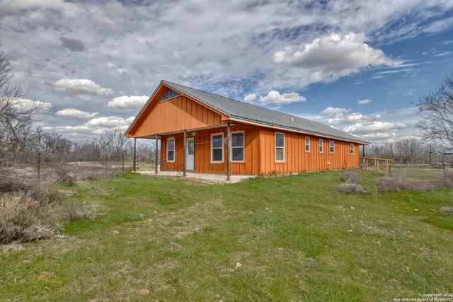 a backyard of a house with plants and large tree