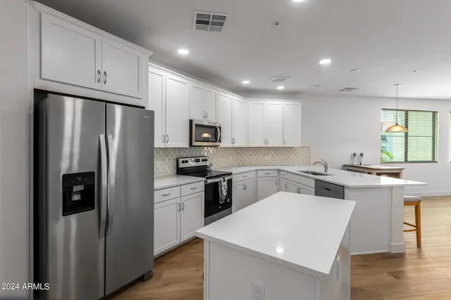 a kitchen with a sink a stove a refrigerator and white cabinets
