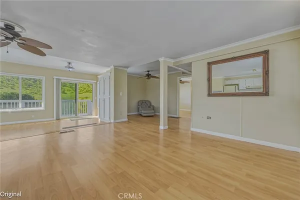 a view of empty room with wooden floor and fan