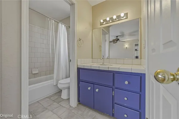 a bathroom with a granite countertop sink a toilet a mirror and shower