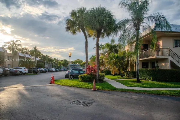 a view of a street with a cars parked and small park