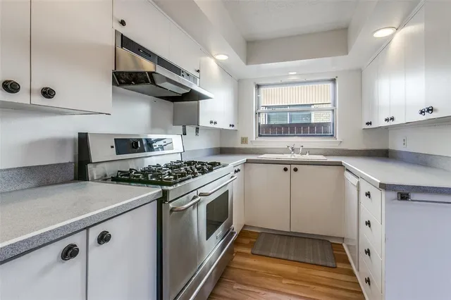 a kitchen with stainless steel appliances a sink a stove and cabinets
