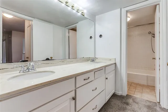 a bathroom with a granite countertop sink mirror and a bathtub